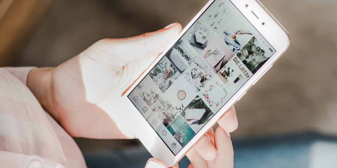 Person holding a smart phone featuring Instagram feed