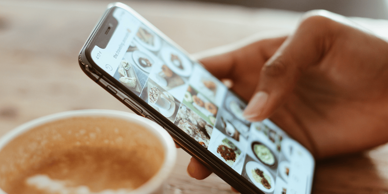 Scrolling through social media Instagram platform on iPhone with coffee